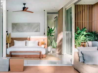 A modern bedroom featuring a concrete floor, minimalist decor, and a cozy seating area with greenery.