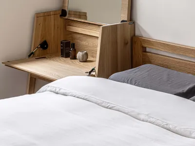 Minimalist bedroom with wooden headboard and wooden desk.