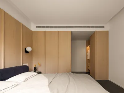 A minimalist bedroom with wooden paneling and a neatly made bed.