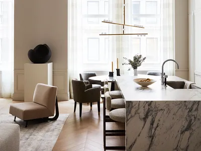 A modern, minimalist kitchen with a marble countertop, featuring sleek furniture and a hanging light fixture.