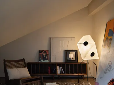 A cozy living room with a wooden armchair, a paper lamp, and a geometric patterned rug.