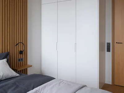 A minimalist bedroom with a bed, white walls, and wooden accents.
