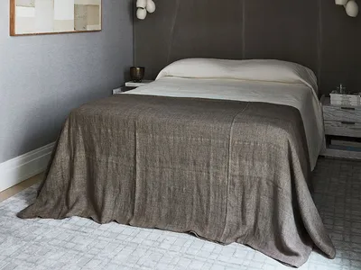 A minimalist bedroom with gray textiles, a bed, and a large abstract painting on the wall.