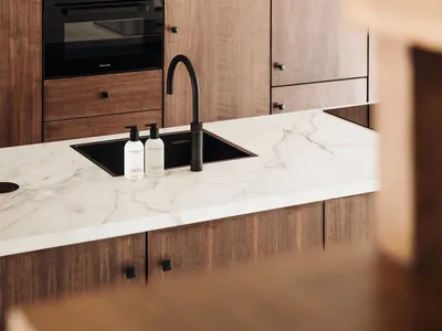 A modern kitchen featuring wooden cabinets and a marble countertop.