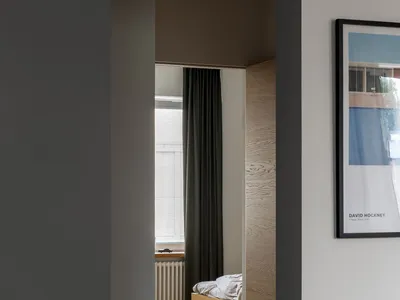 A minimalist bedroom featuring wooden furniture and fabric bedding.