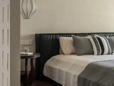 A modern minimalist bedroom with gray textiles and a black leather upholstered bed frame.