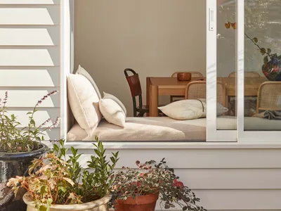 A minimalist living room with neutral tones, showcasing a cozy seating area with cushions and a comfortable window seat.