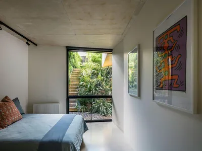Minimalist bedroom with a window offering a view of greenery and stairs.