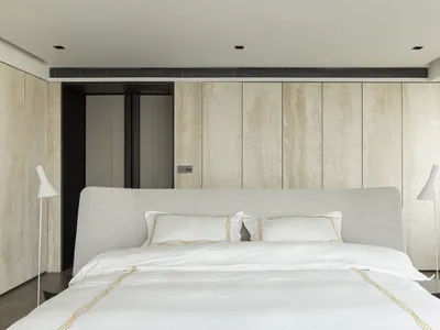 Modern bedroom with light wood texture walls and a neatly made bed.