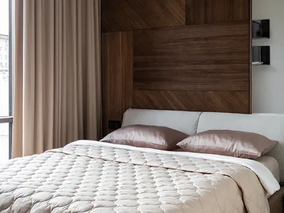 Modern minimalist bedroom with wooden headboard and light-colored bedding.