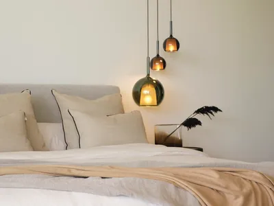 A modern bedroom featuring minimalist design with hanging pendant lights and neutral textiles, creating a cozy atmosphere.