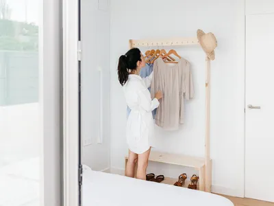 A minimalist bedroom featuring a wooden clothing rack with clothes hanging on it.