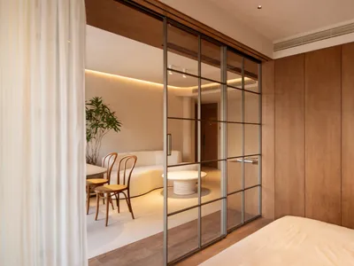 A minimalist bedroom with wooden paneling and a large bed.