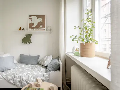 A minimalist bedroom featuring white-walled space, wooden furniture, and gray bedding.
