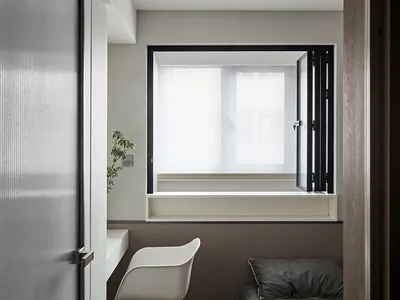 A minimalist bedroom featuring a grey twin bed, window, and white office chair.