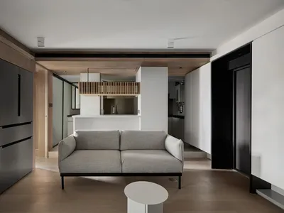 A minimalist living room featuring a grey sofa with wooden flooring and a white circular coffee table.