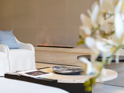 Modern minimalist living room featuring a marble fireplace and coffee table with flowers.