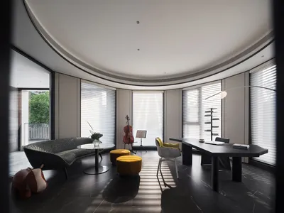 A modern, minimalist home office featuring sleek black furniture, large windows, and a visible cello.