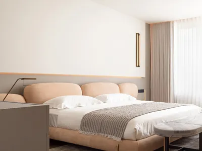 Modern bedroom featuring soft, neutral-toned bedding and furniture.