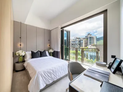 現代臥室，配有白色家具、灰色牆面，以及可眺望都市建築的陽台景觀。