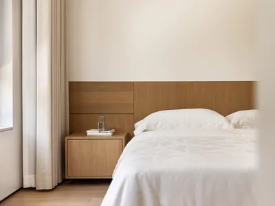 A minimalist bedroom with a wooden headboard and white bedding.