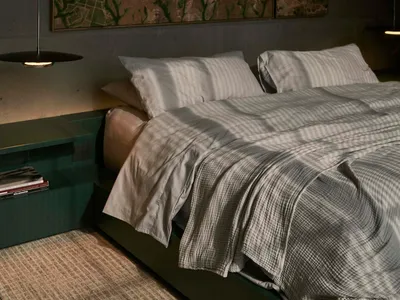 A modern bedroom with gray textiles and a concrete floor.