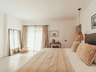 A minimalist bedroom featuring light-colored bedding and woven fabric elements.
