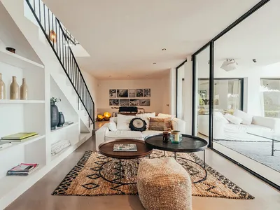 A minimalist living room featuring concrete walls and a large rug.