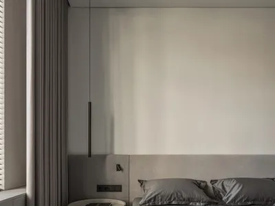 Modern, minimalist bedroom featuring a gray upholstered bed, glass nightstand, and dark wood flooring.