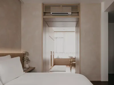 A minimalist bedroom with a white bed, wooden knobs, and a white floor.