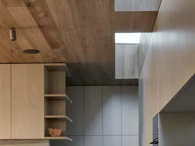 Modern kitchen interior featuring wooden cabinets and concrete flooring.