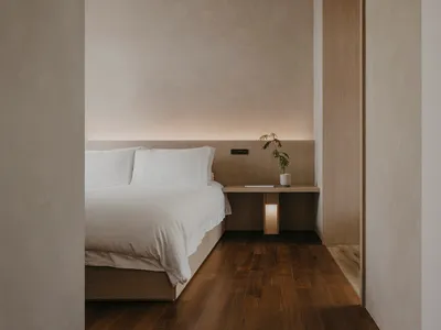 A minimalist bedroom featuring a wooden bed frame and flooring.