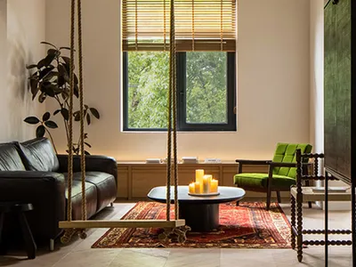 Industrial-style living room featuring wooden furniture, a coffee table with candles, and large windows with greenery outside
