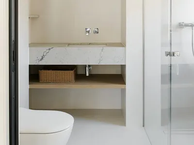 Modern minimalist bathroom with a white marble countertop and white floor tiles.