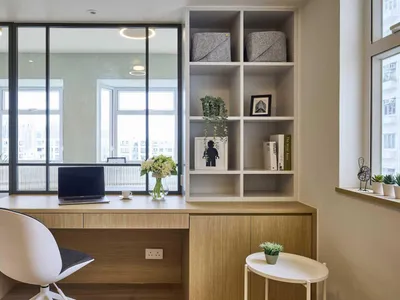 A modern home office with a wooden desk, white chair, and bookshelf.