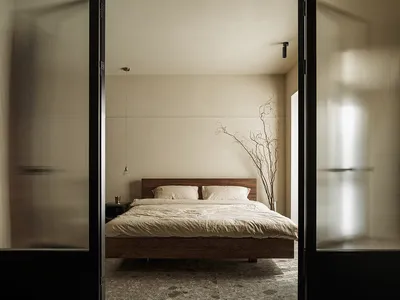 Modern minimalist bedroom featuring concrete and wooden furniture, a cozy ambiance, and a simple yet sophisticated design.
