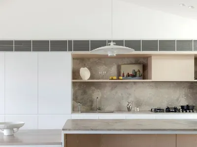 Modern minimalist kitchen with concrete countertops, white cabinets, and wooden flooring.