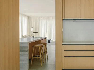 A modern kitchen interior with wooden cabinets and a marble countertop.
