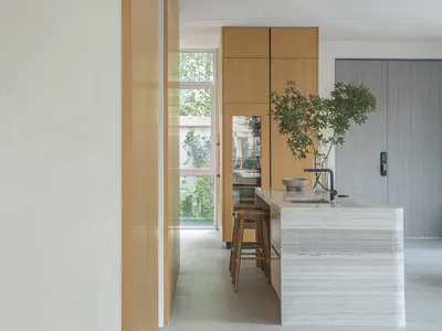 A modern kitchen with white marble countertops and wooden cabinets.