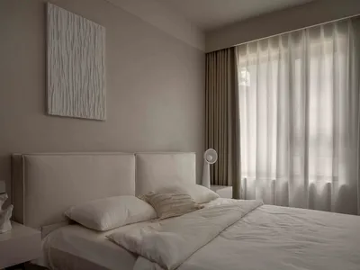 Modern minimalist bedroom with a fabric headboard and white bedding.