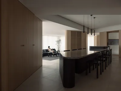 A modern, minimalist residential kitchen with a black island and wooden cabinetry.