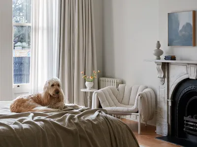 A modern bedroom with a bright and airy atmosphere, featuring a neutral color palette, a comfortable bed, and a cozy fireplac