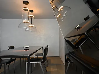現代簡約餐廳室內，配有金屬桌椅、白牆與透明吊燈。