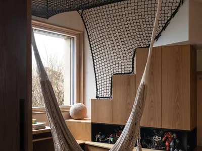 An industrial-style home office with a hammock suspended from the ceiling, featuring wood materials and a cozy workspace.