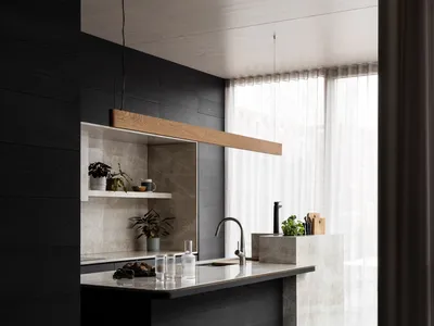 Modern kitchen with marble countertops and black wooden floors.