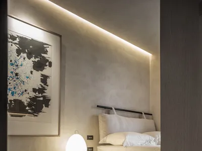 Minimalist bedroom with concrete floor, white bedding, and abstract painting.