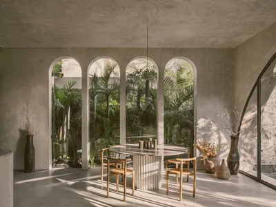 Modern restaurant interior with minimalist design, featuring concrete walls, arched windows, and a glass dining table surroun