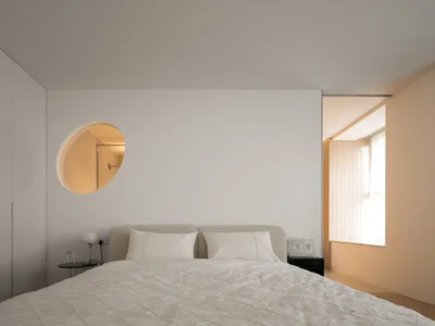 A minimalist bedroom with a fabric-covered bed and light wood accents