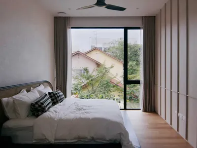 簡約臥室，床鋪配有質感帆布床頭板與木質地板，大型窗戶帶來柔和光線