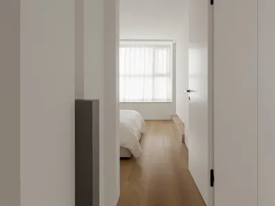 A minimalist bedroom with wood flooring and a bed.